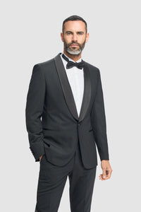 Man wearing a black tuxedo with a white shirt and black bow tie on a light gray background